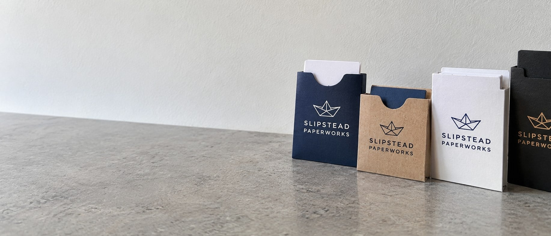 Custom printed hotel key card sleeves, kraft sleeves and business card sleeves on a stone counter
